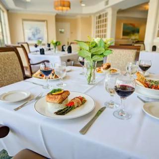 A beautifully set table with plates of gourmet food and glasses of red wine in an elegant restaurant setting.
