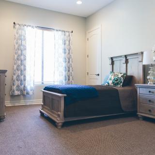 A cozy bedroom featuring a wooden bed, nightstand, and decorative curtains.