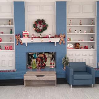 A cozy living room decorated for the holidays, featuring a blue accent wall and festive shelves.