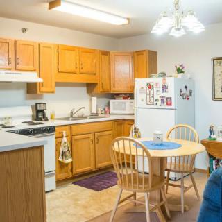 A cozy kitchen with wooden cabinets, a small dining table, and essential appliances.