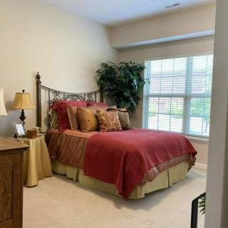 A cozy bedroom with a bed, decorative pillows, and a large window letting in natural light.