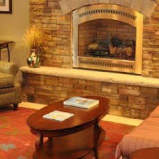 A warm and inviting living room featuring a brick fireplace, cozy seating, and a wooden coffee table.