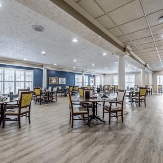 A spacious dining area with neatly arranged tables and chairs, featuring large windows and modern lighting.