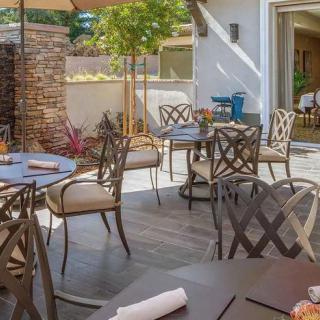 A sunny patio with outdoor seating at a restaurant, featuring tables and chairs.
