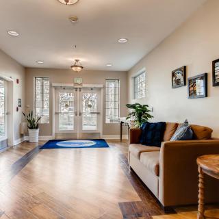 A cozy living room with a sofa, hardwood flooring, and large windows allowing natural light in.