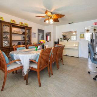 A dining room with a large table surrounded by wooden chairs and a ceiling fan above.
