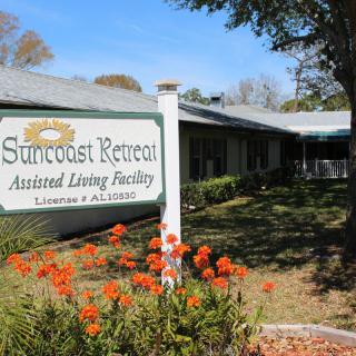 Entrance sign of Suncoast Retreat Assisted Living Facility surrounded by flowers.