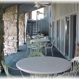 An outdoor patio with tables and chairs, featuring a stone wall and covered seating area.