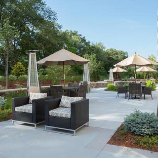 A well-furnished patio with comfortable seating and umbrellas on a sunny day.
