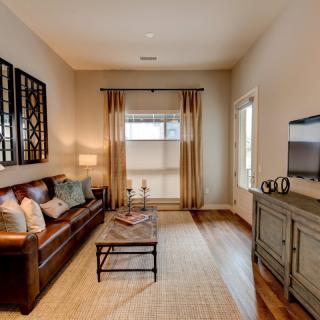 A modern living room with a comfortable sofa, stylish coffee table, and a television, featuring wood flooring and elegant curtains.