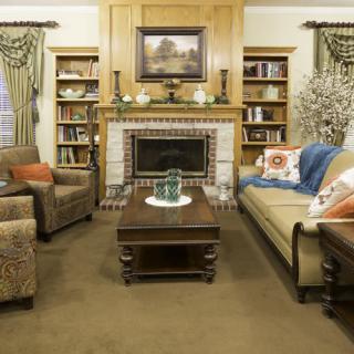A cozy living room with a fireplace, surrounded by bookshelves and comfortable seating.