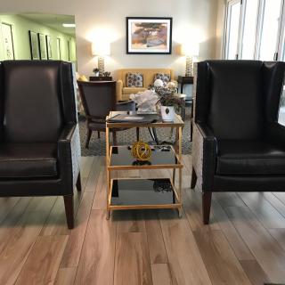 A cozy living room with two black chairs and a small table on wooden flooring.