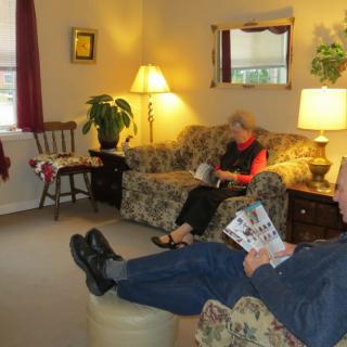 A cozy living room with people relaxing and reading on the sofa.