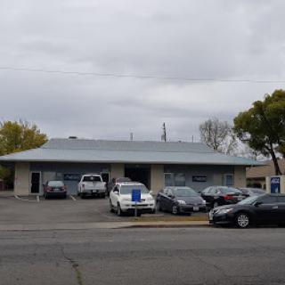 A view of a commercial building with various parked vehicles under a cloudy sky.