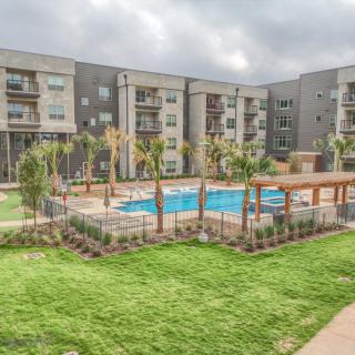 A modern apartment complex with a central swimming pool and landscaped outdoor area.