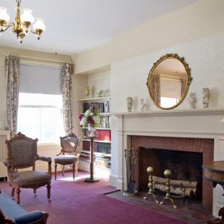 A traditional living room with a fireplace, ornate chairs, and a chandelier.