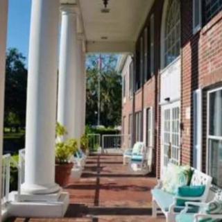 A sunny porch with white columns and comfortable outdoor seating.