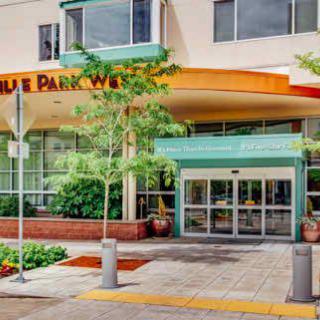 The entrance to a modern building with glass doors and surrounding greenery.