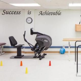 A rehabilitation gym with exercise equipment and motivational quotes on the wall.
