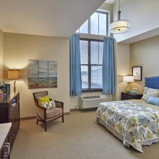 A cozy bedroom with modern decor, featuring a large window, comfortable bed, and stylish furniture.