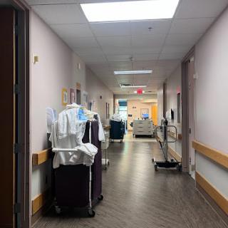 A view of a hospital corridor with medical equipment and staff uniforms.