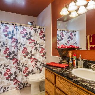 A cozy bathroom with floral shower curtain and warm lighting.