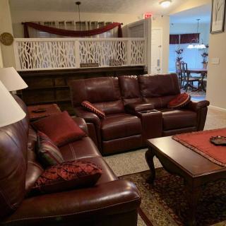A cozy living room featuring leather sofas, a wooden coffee table, and warm decorative accents.