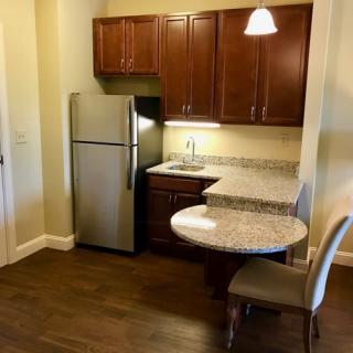 A compact apartment kitchen with stainless steel appliances and wooden cabinets.