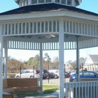 A white gazebo with benches, located in a park setting.