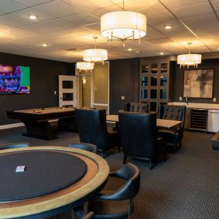 A luxurious game room featuring poker tables, comfortable leather chairs, and elegant chandeliers.