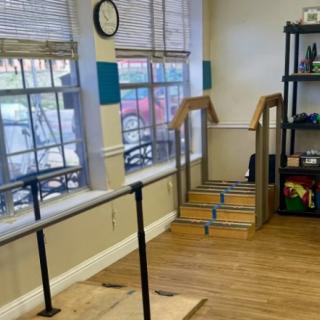 A physical therapy room featuring parallel bars and stairs for rehabilitation exercises.