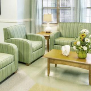 A cozy living room with striped chairs, a sofa, and a wooden coffee table adorned with flowers.