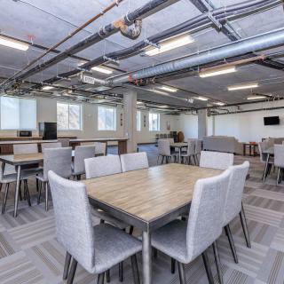 A modern office interior with open workspace featuring tables and chairs.