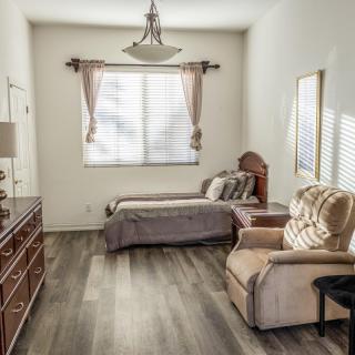 A well-lit bedroom with a bed, comfortable chair, and wooden furniture.