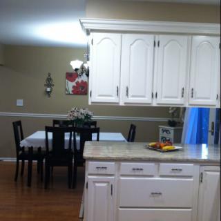 A cozy kitchen with white cabinets and a dining area in the background.