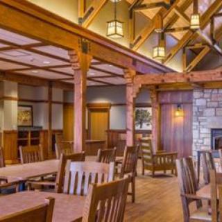 A cozy dining room with wooden interiors and a rustic design, featuring a fireplace and high ceilings.