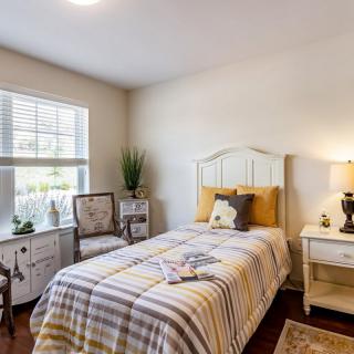 A cozy bedroom with a single bed, decorative accents, and natural light from the window.