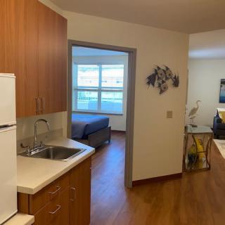 View of an apartment featuring a kitchen area leading to a bedroom with wooden flooring.