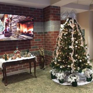 A beautifully decorated Christmas tree with festive ornaments and a cozy fireplace displayed on the TV in a warmly decorated interior.