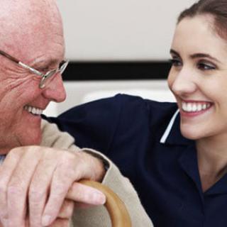 An elderly person smiling and interacting with a caregiver.