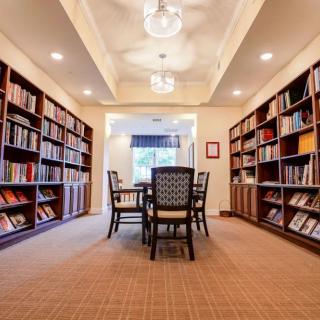 A cozy library room with bookshelves and a central reading table.