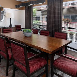 A dining room featuring a wooden table with red upholstered chairs and a plant centerpiece.