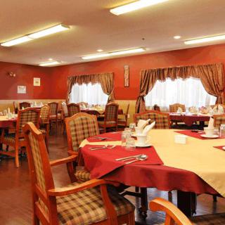 A well-lit dining room with neatly arranged tables and chairs, featuring elegant table settings.