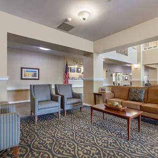 A well-furnished lobby with seating and decor, featuring chairs, a sofa, and a coffee table.