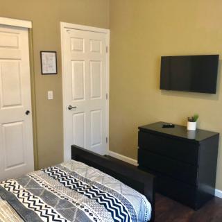 A minimalist bedroom with a bed, TV mounted on the wall, and a dresser.