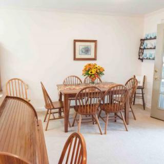 A cozy dining room with a wooden table set and a floral centerpiece.