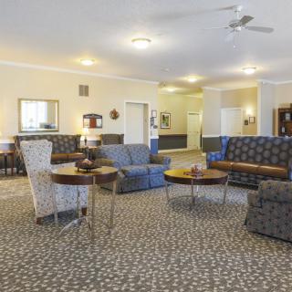 A spacious living room with multiple sofas and a patterned carpet, featuring tables and lamps for a cozy setting.
