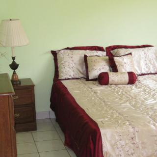 A cozy bedroom with a neatly made bed, featuring elegant bedding and decorative pillows.