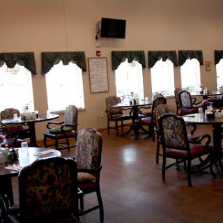 A spacious dining room with decorative furniture and large windows allowing natural light.