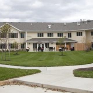 A two-story residential building with a well-maintained lawn and surrounding sidewalks under a cloudy sky.